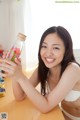 A woman sitting at a table holding a bottle filled with candy.